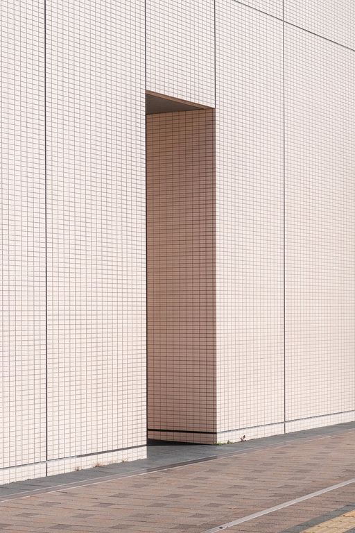 A minimalist photo of a entrance. The building is covered in small pink tiles.